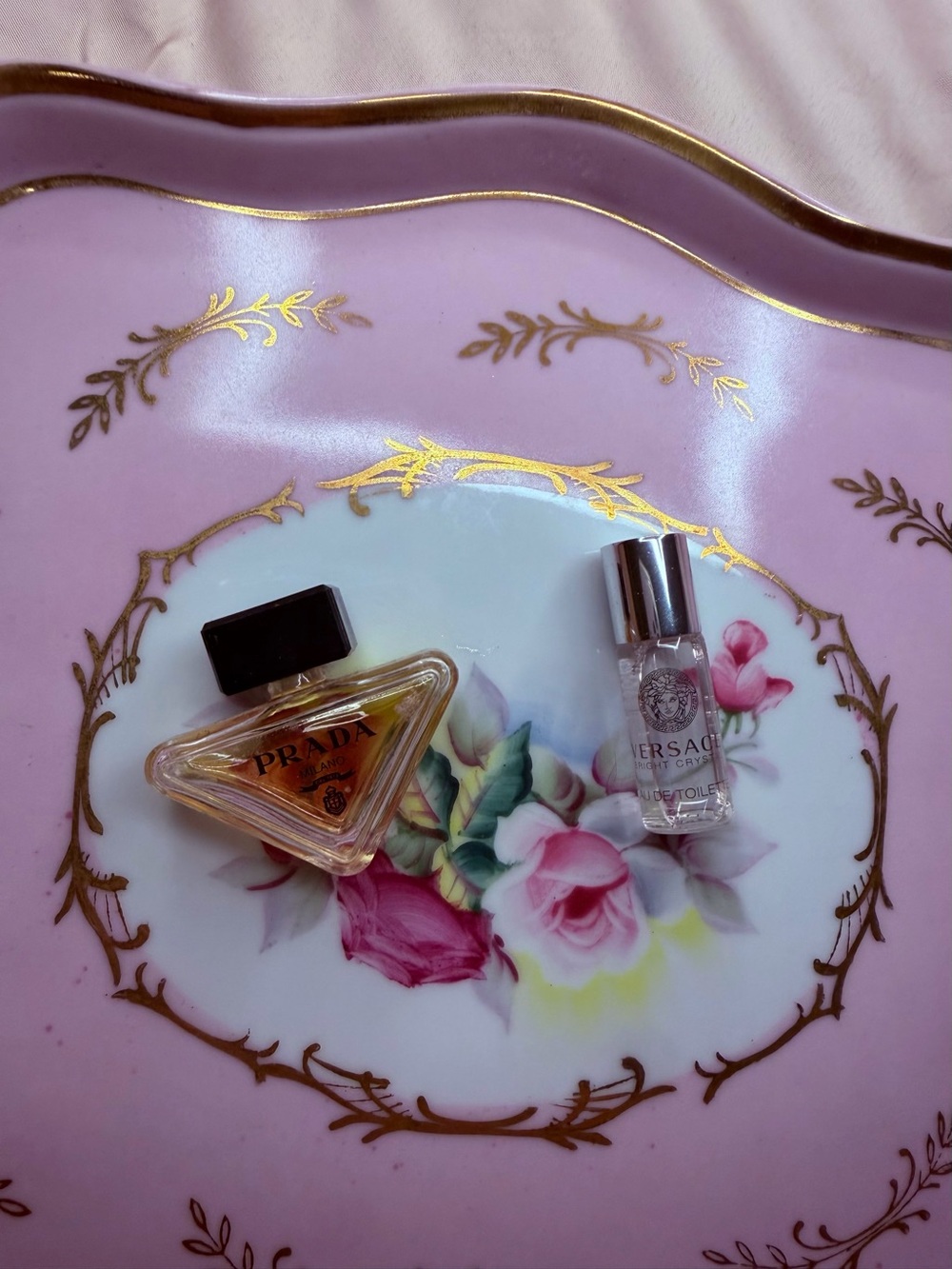 Prada pink and gold perfume bottle on floral tray